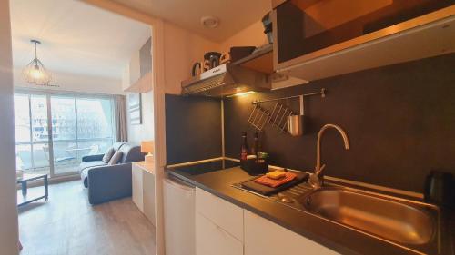 une cuisine avec un évier et un salon dans l'établissement Charmant studio 1ère ligne plages pour 2 Cilmatisation - ROSSIconciergerie - Linge inclus, à La Grande Motte