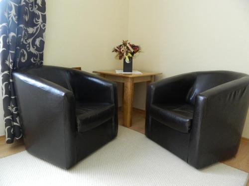 two black leather chairs in a room with a table at Casa Anette in Sovata