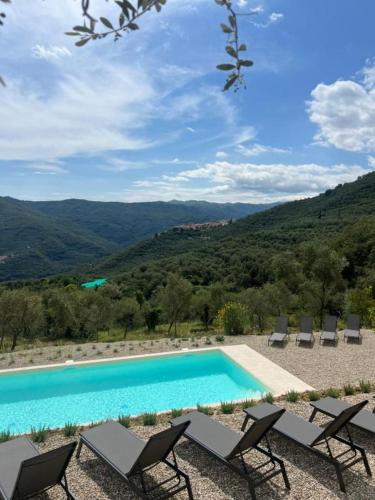 a swimming pool with chairs and a view of mountains at Arya in Chiusanico