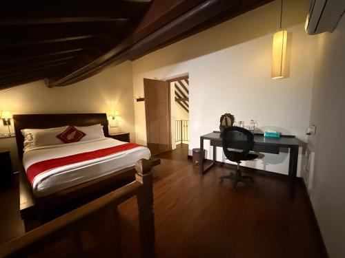 a bedroom with a bed and a desk and a chair at Lar Amorosa Boutique Hotel - Goa in Calangute