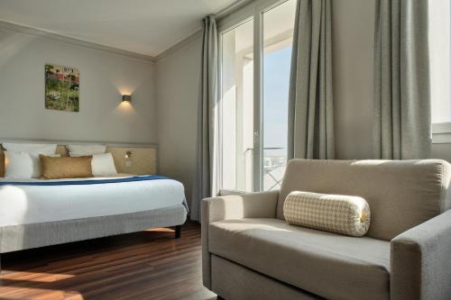 a bedroom with a bed and a couch and a chair at Hotel Atrium by Happyculture in Suresnes