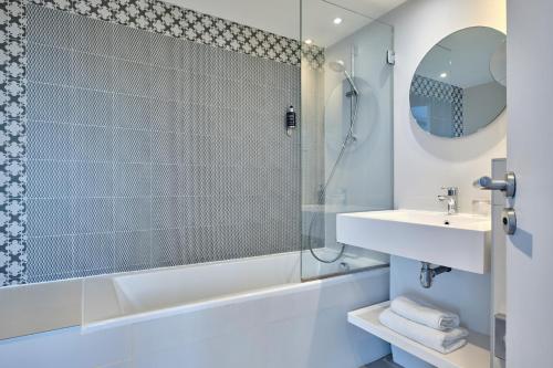 a bathroom with a tub and a sink and a shower at Hotel Atrium by Happyculture in Suresnes