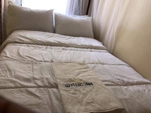 Cama blanca con almohada y toalla extragrande en Idyllic Inn, en Lilongwe