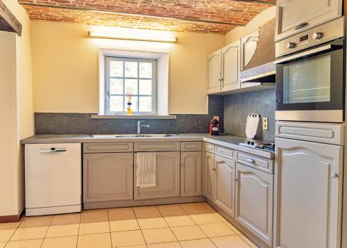 a kitchen with white cabinets and a window at Gîte du Volcan in Namur