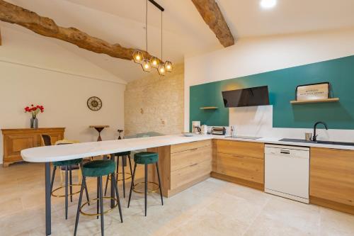 a kitchen with a large white counter and stools at Maison au Domaine du Bilé - Climatisation parking in Solomiac