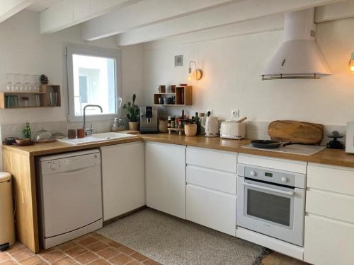 une cuisine avec des armoires blanches et un évier dans l'établissement Charmante maison Charentaise, à Breuillet