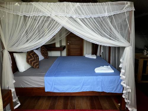a bedroom with a canopy bed with blue sheets and pillows at Steps Garden Resort in Negombo