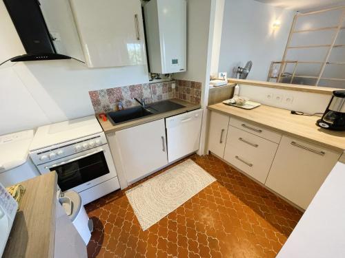 une petite cuisine avec des armoires blanches et un évier dans l'établissement Au cœur du port de Saint-Mandrier, piscine, tennis, charme et confort, à Saint-Mandrier-sur-Mer