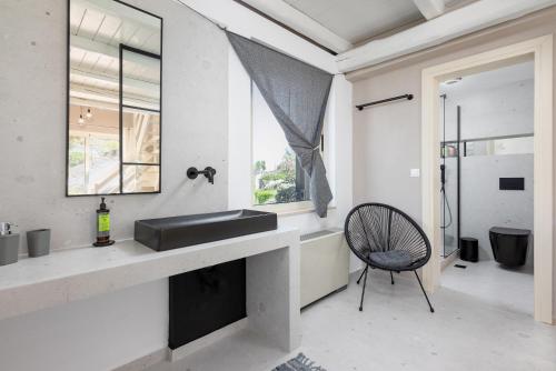 a bathroom with a sink and a chair next to a window at Eliathos Hillside Retreat in Archanes
