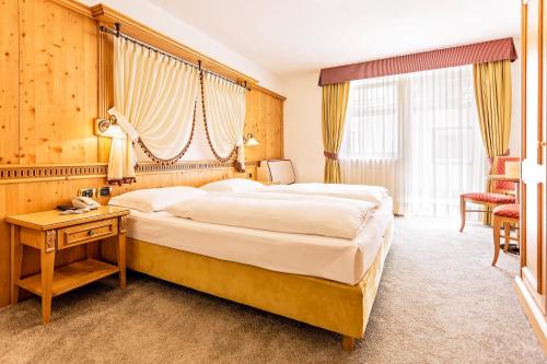 a hotel room with a large bed and a table at Hotel Maria in Ortisei