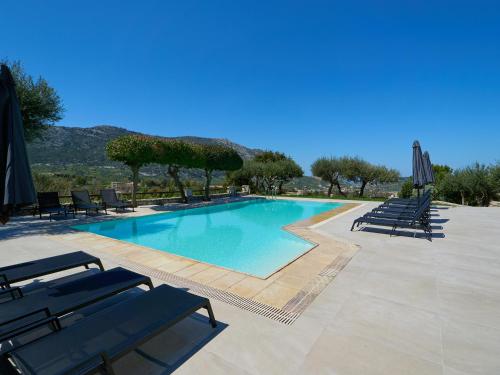 a large swimming pool with chairs and umbrellas at Eliathos Hillside Retreat in Archanes