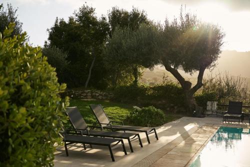 a couple of chairs sitting next to a swimming pool at Eliathos Hillside Retreat in Archanes