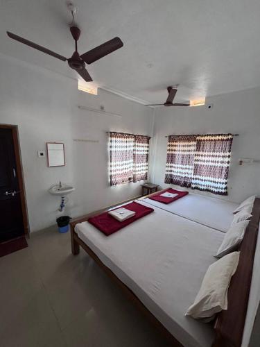 a bedroom with a large white bed with two red mats on it at Aikya homestay in Gokarna