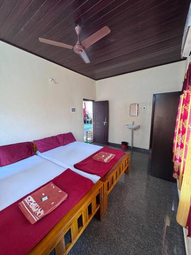 a bedroom with a large bed with red sheets and a ceiling at Aikya homestay in Gokarna