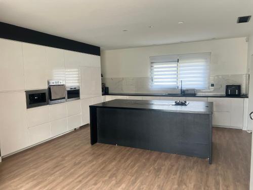 - une grande cuisine avec un îlot noir dans la chambre dans l'établissement Villa avec piscine, à Narbonne