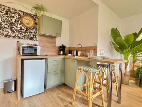 une cuisine avec un comptoir, un four micro-ondes et des tabourets dans l'établissement Studio - Le victoire - aux portes du Futuroscope, à Chasseneuil-du-Poitou