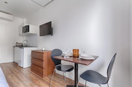 une petite cuisine avec une table et des chaises dans une pièce dans l'établissement TBS 312 - Charming studio near Marais district, à Paris