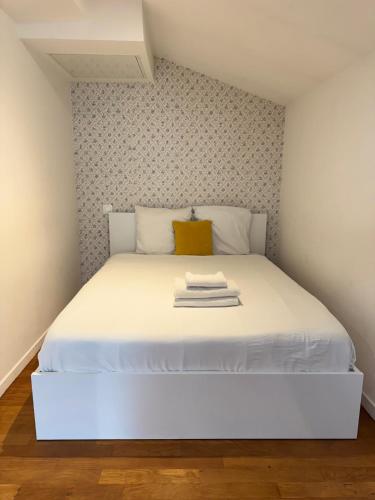 - une chambre avec un lit blanc et un oreiller jaune dans l'établissement L'Agua, centre-ville de Dax, à Dax