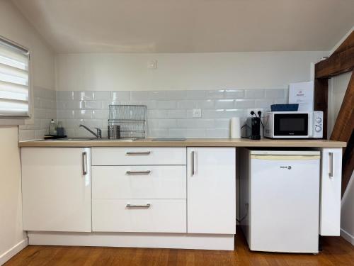 une cuisine avec des armoires blanches et un micro-ondes dans l'établissement L'Agua, centre-ville de Dax, à Dax