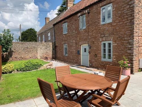 a wooden table and chairs in front of a brick house at Sunny 4-bedroom cottage with South facing garden - Sunflower Cottage in Draycott