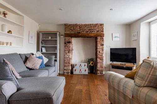 a living room with a couch and a television at Sunny 4-bedroom cottage with South facing garden - Sunflower Cottage in Draycott