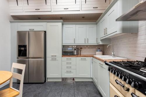 a kitchen with white cabinets and a stainless steel refrigerator at Sunny 4-bedroom cottage with South facing garden - Sunflower Cottage in Draycott