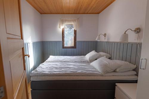 a bed with white sheets and pillows in a room at Kraatterimökki in Lappajärvi