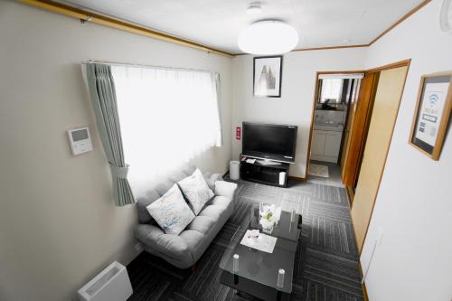 a living room with a couch and a tv at Guest House平安 in Nagoya