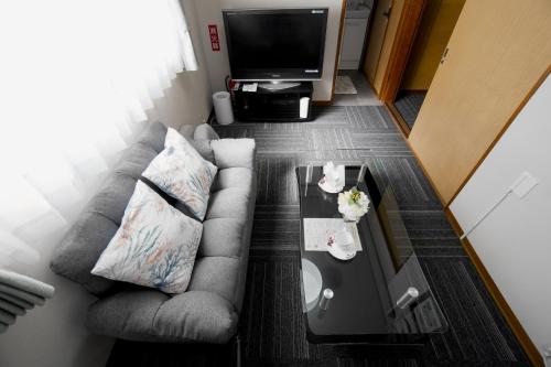 a living room with a couch and a tv at Guest House平安 in Nagoya