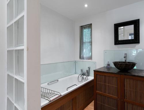 a bathroom with a bath tub and a sink at Churchlands in Kirdford
