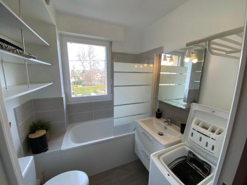 une salle de bain blanche avec une baignoire et un lavabo dans l'établissement La Cabourgeaise-Proche Thalasso et Centre de Cabourg, à Cabourg