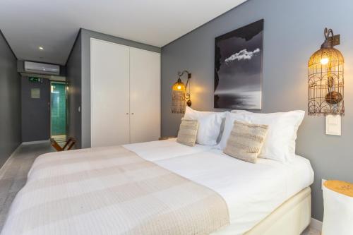 a bedroom with a large white bed with two pillows at Casa da Praça Guest House in Sesimbra