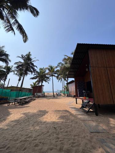 a beach with benches and palm trees and a building at Sector 47 Beachfront in Gokarn