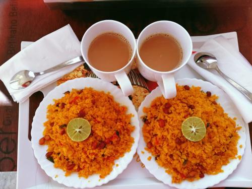 two cups of tea and two plates of rice at Krishnabalram wellness & Ayurveda centre in Rishīkesh