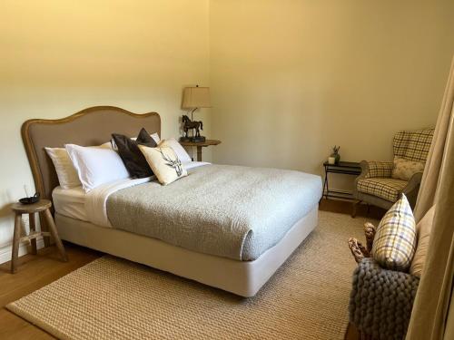 a bedroom with a bed with pillows and a chair at Ciel House - French style in Angaston