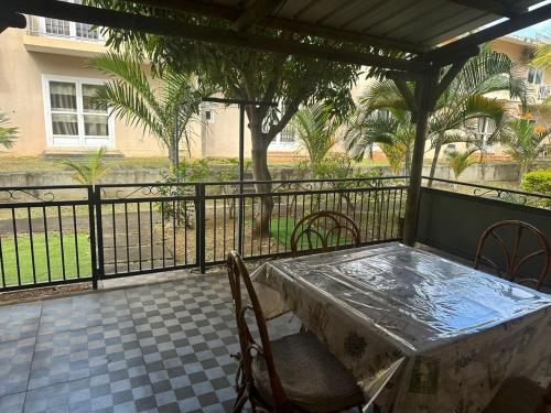 a porch with a table and chairs and a fence at La Casa Familia in Grand Gaube