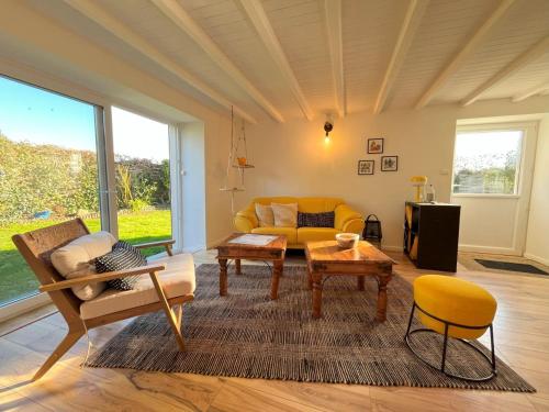 un salon avec un canapé jaune et une table dans l'établissement Maison rénovée 3 chambres pour 5 personnes, proche mer, parking, à Cléder