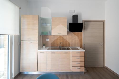 a kitchen with wooden cabinets and a sink at Homiday - Residence Venere in Alba Adriatica