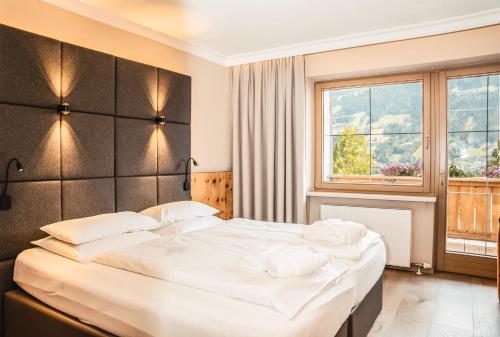 a bedroom with a large bed and a large window at HELD - Hotel & Spa , 4 Sterne Superior, Zillertal in Fügen
