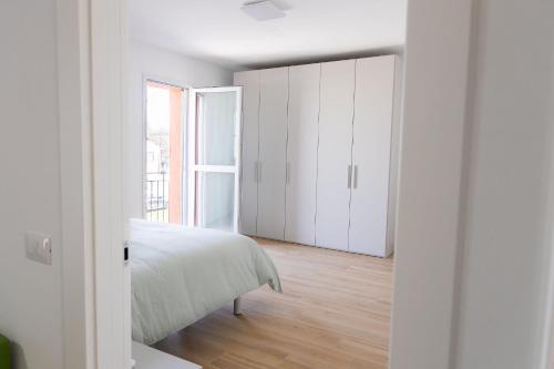 a white bedroom with a bed and a window at Il Nido Verde Parcheggio Privato Cortile in Piacenza