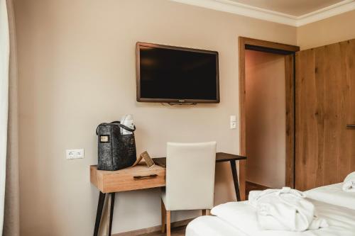 a hotel room with a desk and a tv on the wall at HELD - Hotel & Spa , 4 Sterne Superior, Zillertal in Fügen