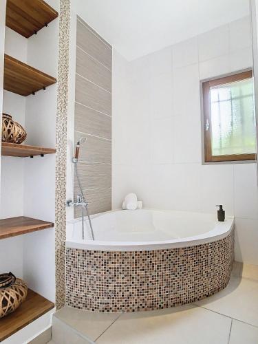 La salle de bains est pourvue d'une baignoire et de murs blancs. dans l'établissement Villa Bamboo Zen, à Cannes