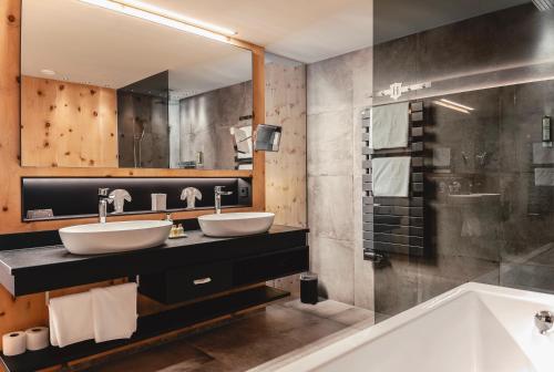 a bathroom with two sinks and a tub and a mirror at HELD - Hotel & Spa , 4 Sterne Superior, Zillertal in Fügen
