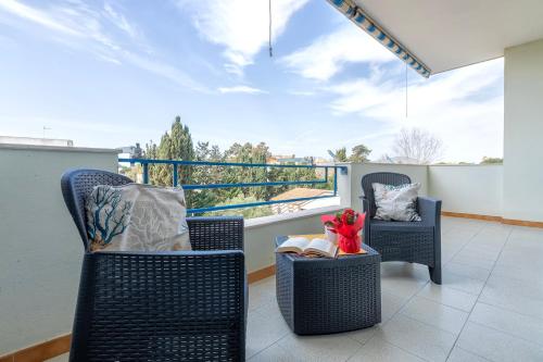 a balcony with two chairs and a table with a book at Txa Vì - Terrace with sea view in Alghero