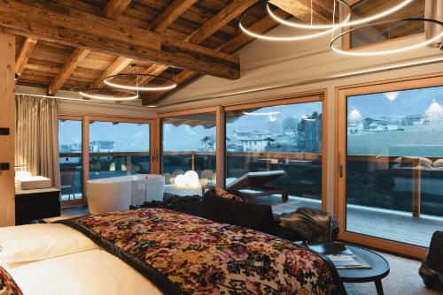 a bedroom with a bed and a large window at HELD - Hotel & Spa , 4 Sterne Superior, Zillertal in Fügen