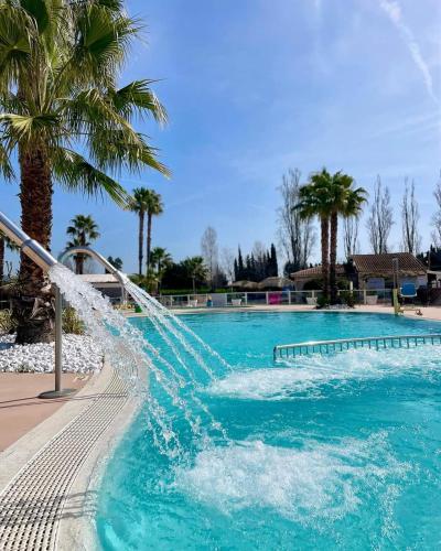- un toboggan aquatique dans une piscine bordée de palmiers dans l'établissement Mobilhome beaux volumes ES40, à Fréjus