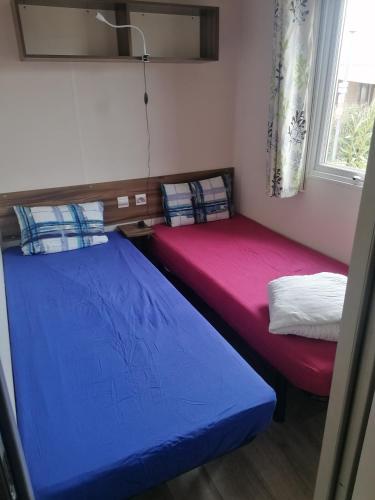 deux lits dans une petite pièce avec une fenêtre dans l'établissement Mobilhome beaux volumes ES40, à Fréjus