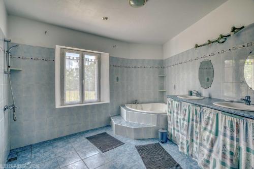 une salle de bain avec deux lavabos et une baignoire et une baignoire dans l'établissement Authentic Charming House WIFI Swimming Pool 10 ppl, à Beaumont-du-Périgord