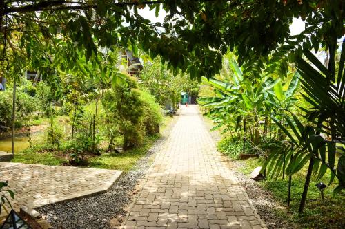 a brick path in a garden with trees at Steps Garden Resort in Negombo