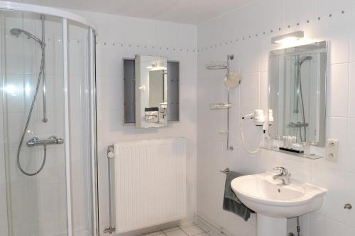 a white bathroom with a shower and a sink at Hotel Vijfwegen in Roeselare